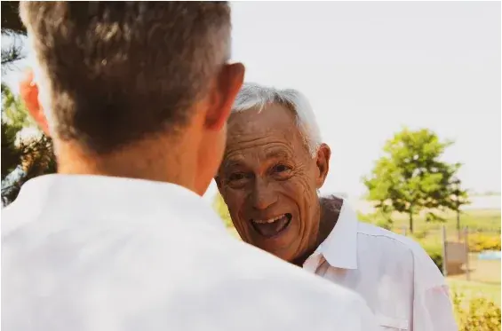 An older man smiling outdoors in conversation