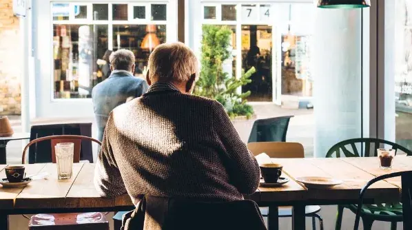 An older man seated at a kitchen table